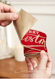 Detail of red velvet Christmas ribbon with gold Merry Christmas lettering and satin back