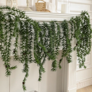 Artificial cedar garland with pine cones hanging on a fireplace mantel for holiday decor