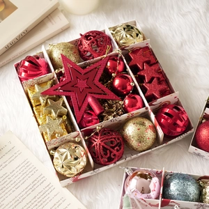 Détail de boules de Noël rouges et dorées dans leur coffret sur décor en peluche blanche