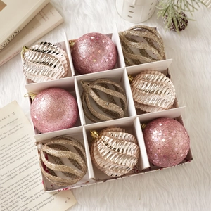 Détail de 9 boules de Noël roses et champagne présentées dans un coffret cadeau blanc