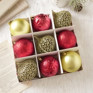 Gros plan de boules de Noël rouges et dorées dans une boîte avec diverses textures festives