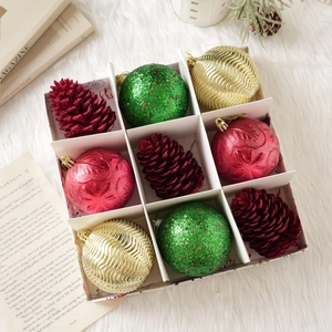 Détail de boules de Noël rouges, vertes et dorées en coffret avec des pommes de pin