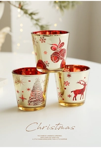 Gros plan de trois photophores festifs en verre avec motifs dorés d'élans et de flocons