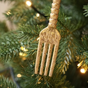 Vintage gold cutlery fork ornaments hanging on Christmas tree with warm festive bokeh lighting