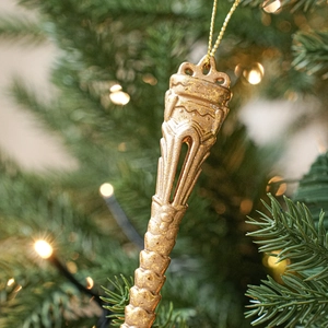 Golden vintage textured Christmas tree ornament with glitter finish hanging on a green branch