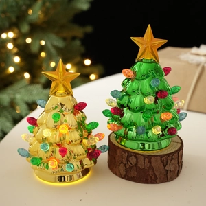 Close-up of glowing green and gold Christmas tree desk lamps with festive background