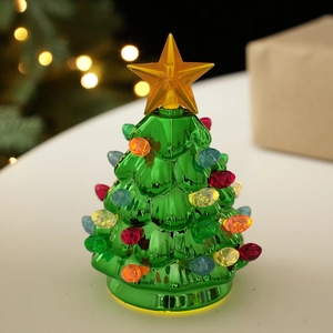 Close-up of a glowing ceramic Christmas tree with colorful lights on a festive table