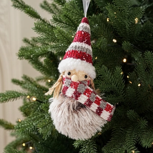 Detail of plush Christmas gnome with red knitted hat and warm holiday tree background