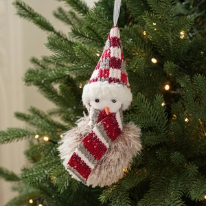 Close-up of plush Christmas snowman ornament with knitted hat hanging on a festive tree