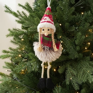 Close-up of plush Christmas girl ornament with striped knit hat on festive green tree
