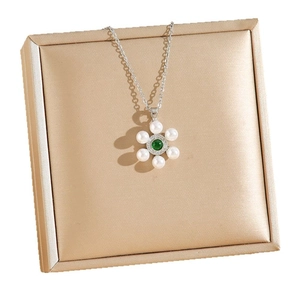Vintage 18K gold plated emerald and pearl floral pendant necklace on a jewelry box