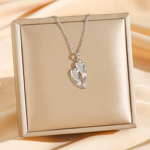 Gros plan d'un collier cœur aile d'ange en argent avec zircons sur tissu en soie dorée