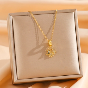 Golden titanium necklace with crescent moon, sun and star pendants on silk background