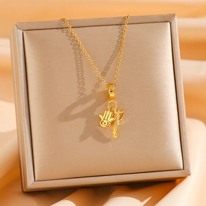 Macro detail of golden Hamsa hand and feather pendant on a stylish titanium steel chain