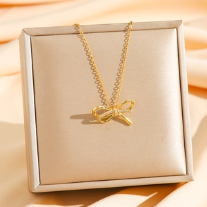 Collier élégant avec nœud doré et cristaux sur un coffret cadeau de luxe champagne