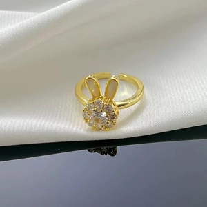 Adjustable gold plated bunny ring with white zircon flowers on white fabric backdrop