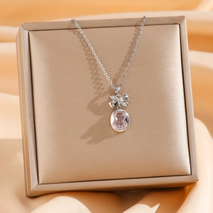 Collier avec pendentif ourson mignon, nœud et pierre rose sur boîte à bijoux dorée