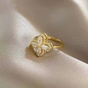 Bague fleur dorée élégante avec pétales en zircon sur fond de soie luxueux