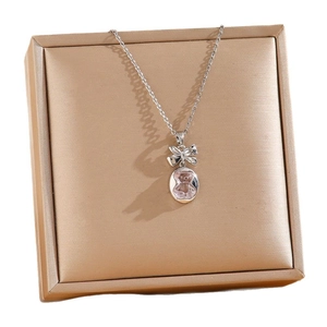 Collier mignon ours rose avec pendentif nœud argenté sur boîte à bijoux dorée