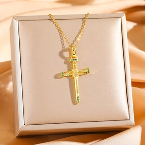 Elegant gold cross necklace with green zircon crystals on champagne satin background