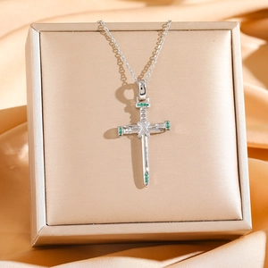 Silver cross necklace with green zircon and nail design on luxury jewelry box