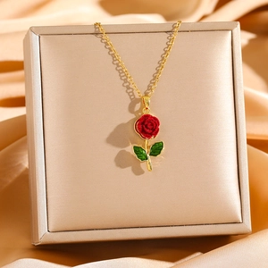 Macro detail of luxury rose pendant with red velvet petals and green leaves on gold chain