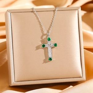 Detail of cross pendant with micro-pave zircons and green heart-shaped gemstones
