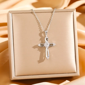 Detailed close-up of a silver hollow cross necklace with zircon stones on a gold stand