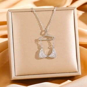 Elegant silver bikini pendant necklace with sparkling zircons on a champagne silk background