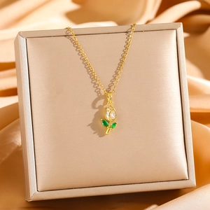 Elegant gold tulip necklace with crystal bud and green leaves on silk backdrop