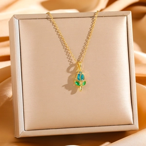 Elegant gold tulip pendant necklace with light blue petals on beige jewelry box