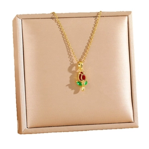 Elegant gold tulip necklace with red enamel flower pendant on satin jewelry box lining