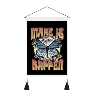 Dettaglio arazzo farfalla con testo 'MAKE IT HAPPEN', asta in legno e nappe nere
