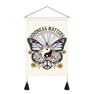 Dettaglio dell'arazzo farfalla con testo Kindness Matters e nappe decorative nere lucide