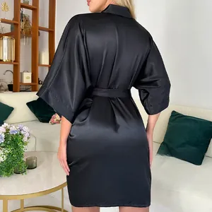 Détail d'un peignoir en satin noir soyeux avec ceinture dans un décor intérieur élégant