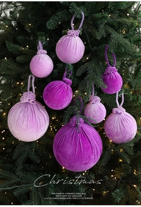 Close-up of purple velvet Christmas baubles with elegant hanging ribbons on a tree