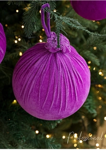 Close-up of purple velvet Christmas ball ornaments hanging on a festive decorated tree