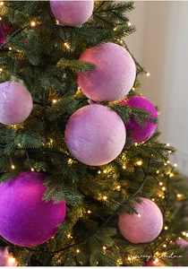 Close-up of pink velvet Christmas ornaments with a soft texture on a glowing tree