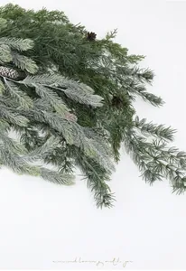 Detail of lifelike PE pine branches with snowy needles and natural brown pinecones
