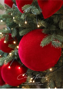 Gros plan sur une boule de Noël en velours rouge suspendue à un sapin avec lumières