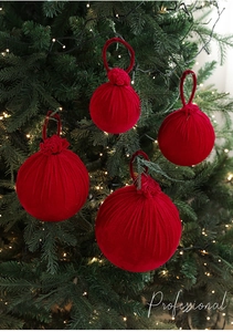 Détail de boules de Noël en velours bordeaux suspendues sur une branche de sapin décorée
