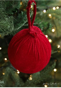 Gros plan d'une boule de Noël en velours bordeaux avec attache sur sapin de fête