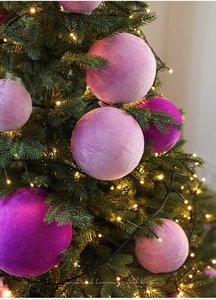 Détail des boules de Noël en velours violet et rose sur un sapin avec des LED