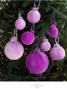 Détail de boules de Noël en velours violet suspendues avec lumières chaleureuses