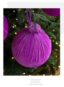 Détail d'une boule de Noël en velours violet suspendue à une branche de sapin festive