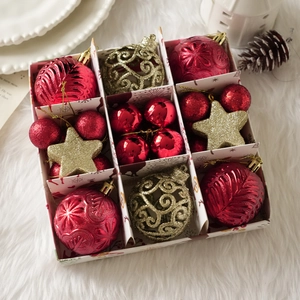 Detalle de bolas de Navidad rojas y doradas en una caja de regalo con copos blancos