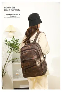 Détail d'un sac à dos vintage marron montrant la sangle de bagage et les multiples poches