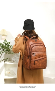 Détail d'un grand sac à dos en cuir marron avec plusieurs compartiments zippés