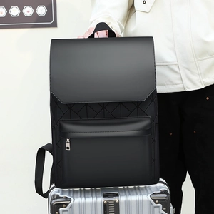 Detail of black geometric embossed backpack handle resting on a silver suitcase