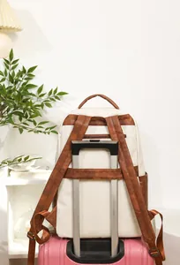 Sac à dos avec sangle de bagage détaillée fixée sur la poignée d'une valise trolley